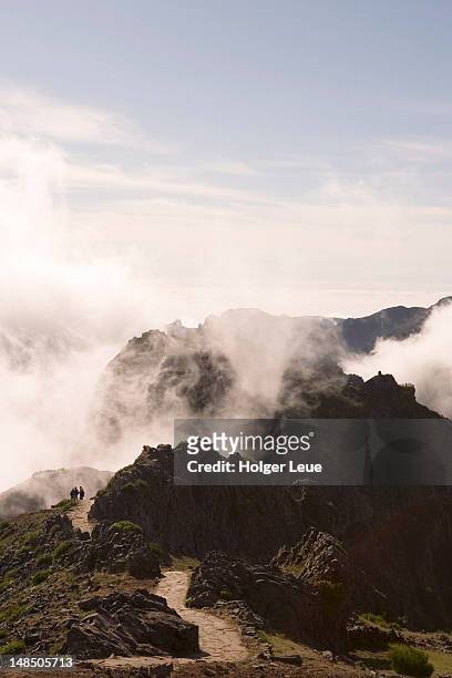 hikers on track between pico do arieiro and pico ruivo mountains. - pico do arieiro fotografías e imágenes de stock