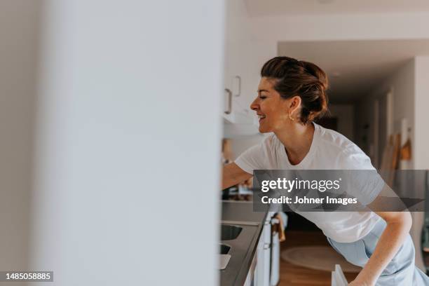smiling woman in kitchen looking away - cleaner smiling stock pictures, royalty-free photos & images