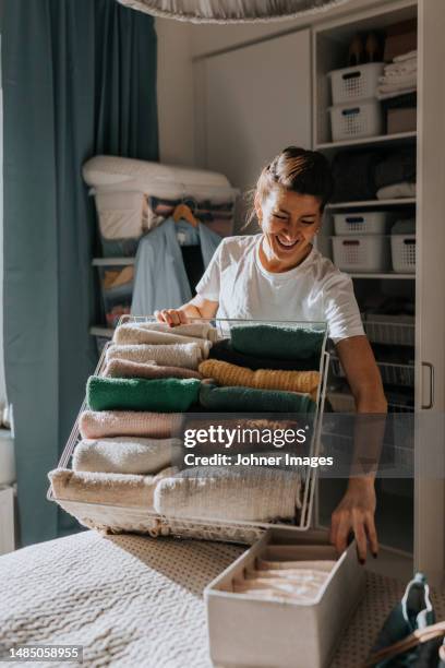 woman holding basket with clothes, open wardrobe in background - kleiderschrank frau stock-fotos und bilder