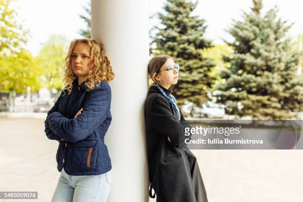 offended at each other girls standing on opposite sides of the column and ignoring each other - furious stock-fotos und bilder