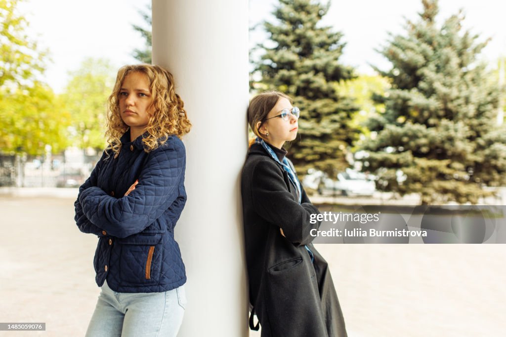 Offended at each other girls standing on opposite sides of the column and ignoring each other