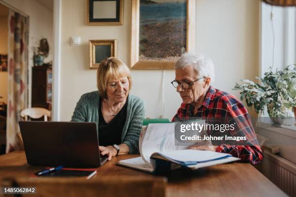 senior couple using laptop at home - accesorio financiero fotografías e imágenes de stock