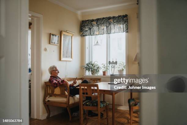 senior man using smart phone at home - einzelner senior stock-fotos und bilder