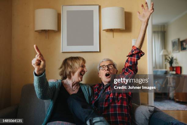 senior couple sitting on sofa and singing - singing stock pictures, royalty-free photos & images