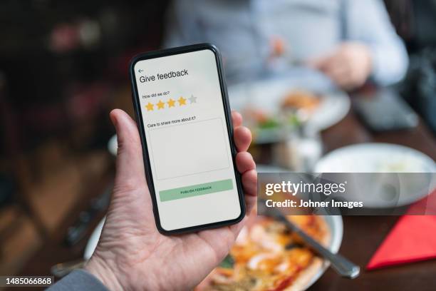 person holding smart phone with restaurant rating app - feedback imagens e fotografias de stock