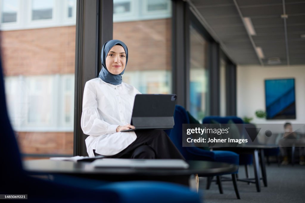 Businesswoman in hijab using digital tablet in office