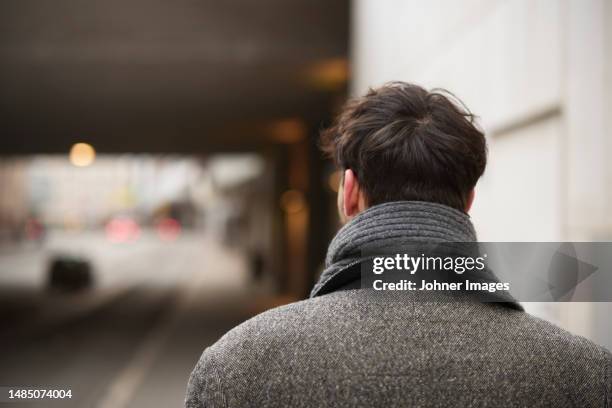 rear view of man walking in street - abrigo gris fotografías e imágenes de stock