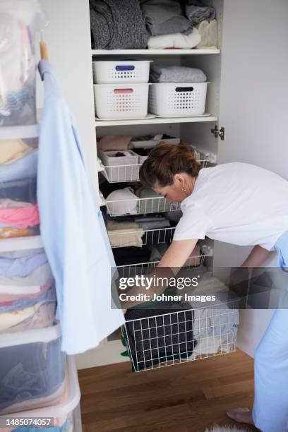 woman putting basket in wardrobe - storage basket stock pictures, royalty-free photos & images