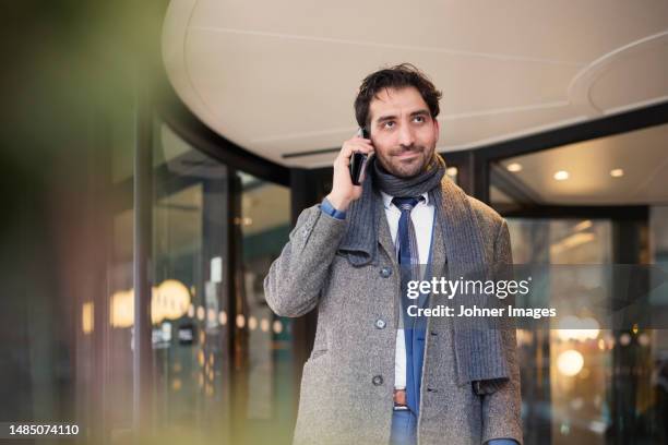 businessman talking on phone outdoors - abrigo gris fotografías e imágenes de stock