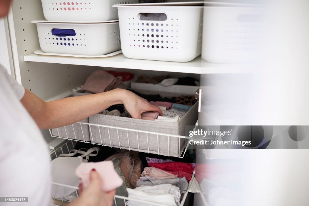 Woman's hands putting clothes into basket