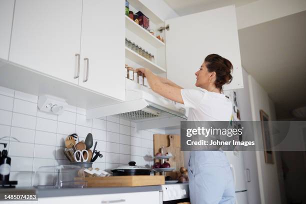 woman checking spices in cupboard - escaparate fotografías e imágenes de stock
