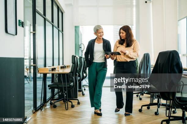frauen unterschiedlicher ethnien arbeiten in einem modernen büro zusammen - business man woman walking stock-fotos und bilder