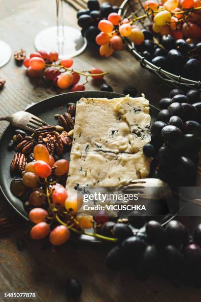 close up of mature gorgonzola cheese  on plate with grapes, nuts, honey and fork - gorgonzola stockfoto's en -beelden