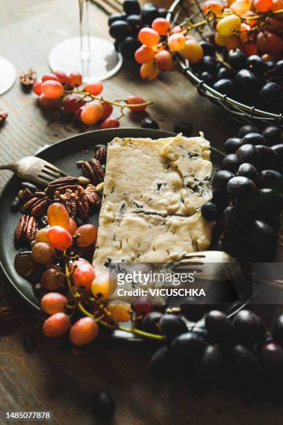 close up of mature gorgonzola cheese  on plate with grapes, nuts, honey and fork - gorgonzola stock pictures, royalty-free photos & images