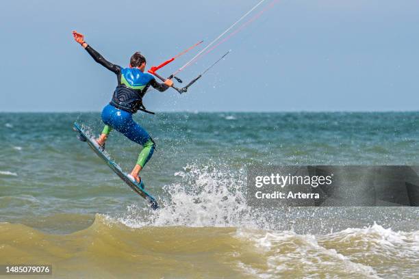 Kitesurfing showing kiteboarder. Kitesurfer on twintip board jumping on the North Sea on a windy day.