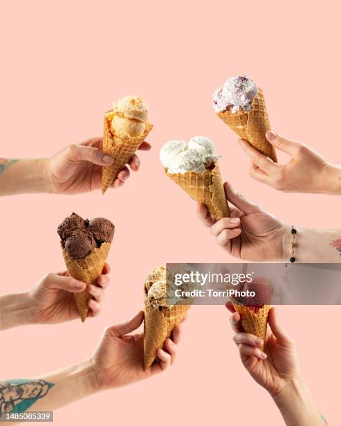 many hands holding ice cream cones with different scoops of ice cream on pink background - gelato stock-fotos und bilder