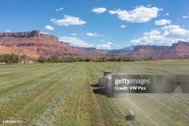 Aerial view of a rancher baling hay in an alfalfa field on a ranch in the desert near Moab, Utah.