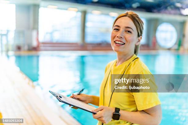 female lifeguard standing while looking at camera. - red guards stockfoto's en -beelden