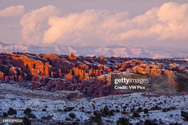 Snowy Fiery Furnace viewed from the south with the snow-capped Book Cliffs behind. Arches National Park, Moab, Utah.