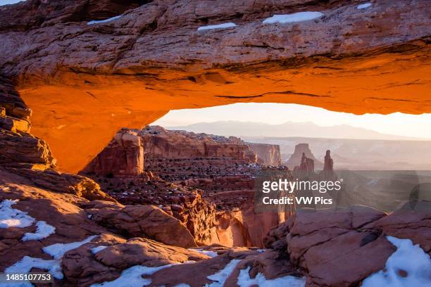 Washer Woman Arch, Monster Tower & Airport Tower in winter through Mesa Arch in Canyonlands National Park, Utah. La Sal Mountains behind.