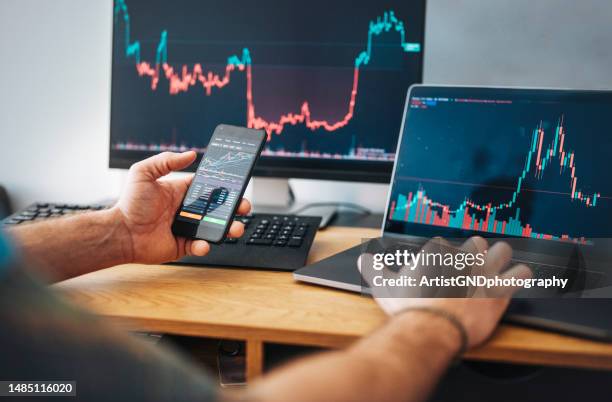 man looking at currency trading app on his smart phone from his home office. - finance and economy stock pictures, royalty-free photos & images