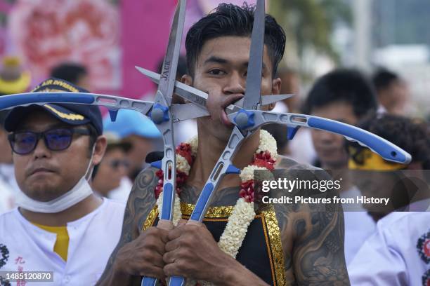 Garlanded participant in a procession during the Vegetarian Festival in Phuket Town, a so-called Mah Song or spirit medium, his cheeks ritually...