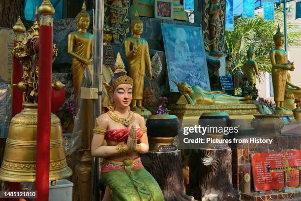 Prayer shrine at Wat Ratchathiwat, Bangkok, with a female figure performing a traditional Thai wai .