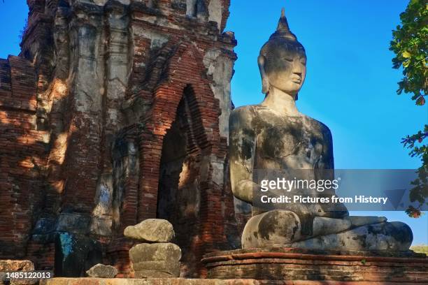 Buddha statue at Wat Mahathat in Ayutthaya Historical Park in the former capital city of Ayutthaya. Wat Phra Mahathat was built during the reign of...