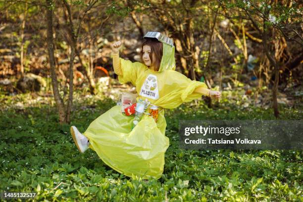 little girl walking in forest playing dress-up in outfit made from plastic and garbage - trash bag dress stock pictures, royalty-free photos & images