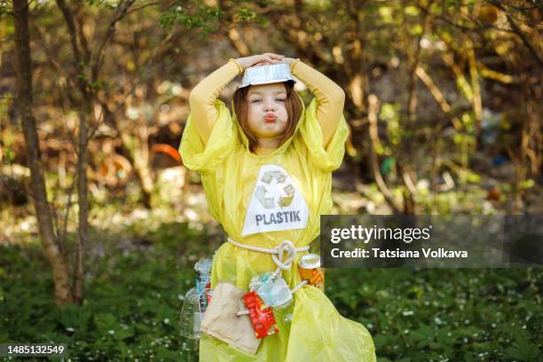 small girl posing wearing yellow plastic dress with big recycling sign - trash bag dress stock pictures, royalty-free photos & images