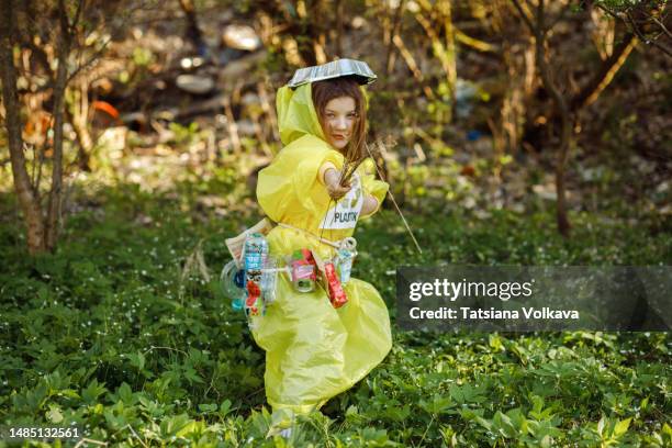 small girl in costume made of garbage playing with sticks and collecting cans to help clean environment - trash bag dress stock pictures, royalty-free photos & images