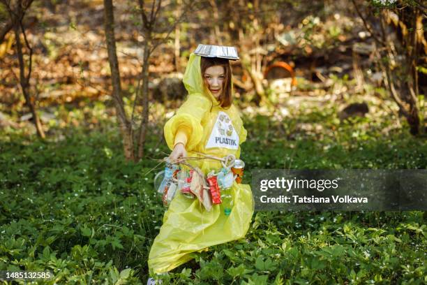 small girl holding sticks collecting garbage in local park - trash bag dress stock pictures, royalty-free photos & images