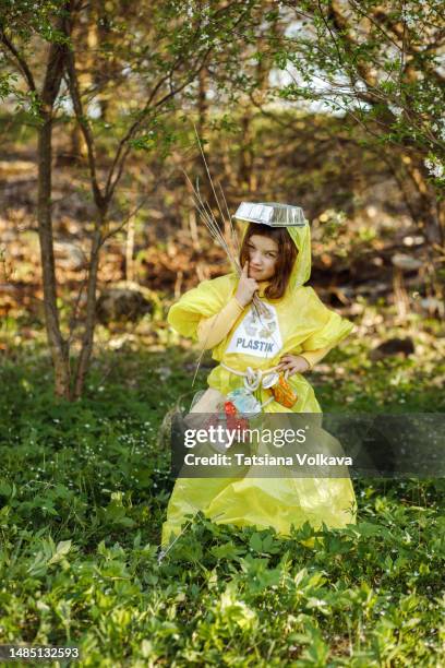 little girl wearing plastic dress holding sticks posing for picture - trash bag dress stock pictures, royalty-free photos & images
