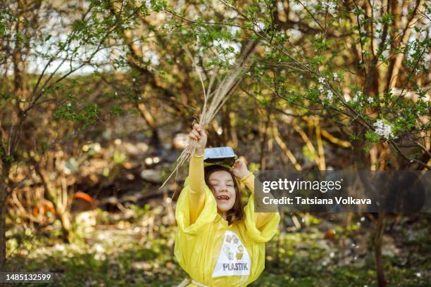 small girl playing with sticks and garbage found among trees and grass - trash bag dress stock pictures, royalty-free photos & images