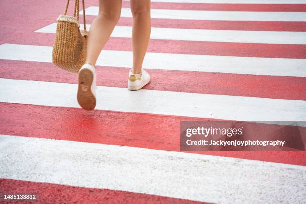 low section of woman crossing road - weiblichkeit stock-fotos und bilder