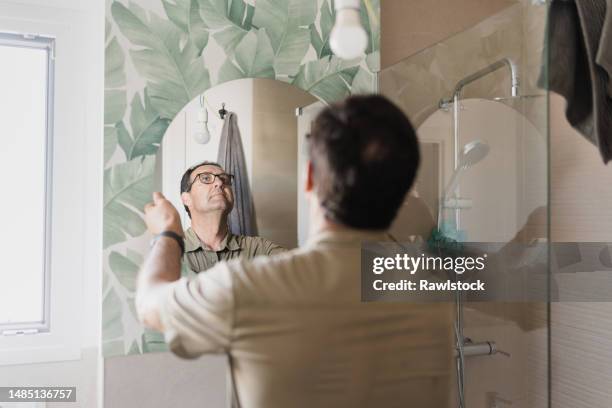 portrait of a person placing a mirror in the bathroom. home decoration concept - deko bad stock-fotos und bilder
