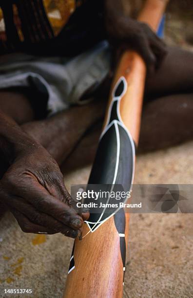 aboriginal craftsman working on digeridoo. - aboriginal artwork stockfoto's en -beelden