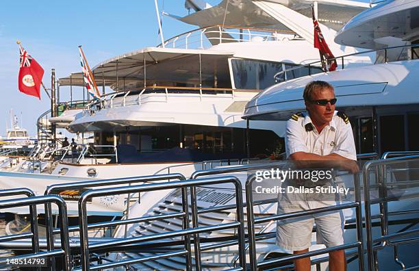 crewman of luxury yacht leaning against railing, port hercule. - boat crew stock pictures, royalty-free photos & images