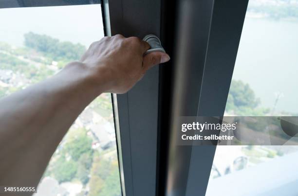 human hands touch the handle of the window - window frame stock pictures, royalty-free photos & images