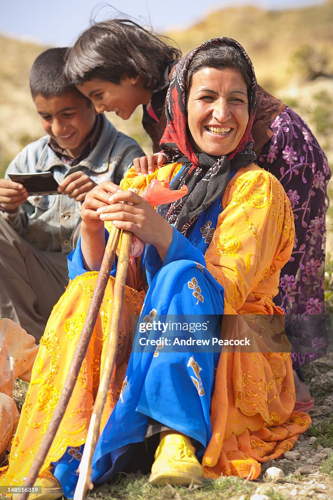 Kurdish woman and children goat herders resting near Qareh Kalisa ('Black Church'). The children are looking at an instant photo print given to them.