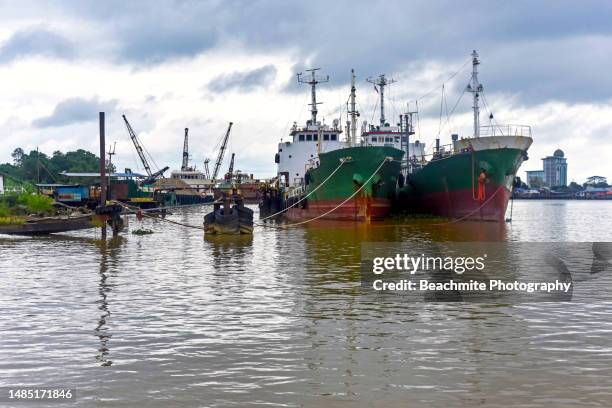 ships moored at a riverside jetty on a cloudy morning in sibu, sarawak - sibu river stock pictures, royalty-free photos & images