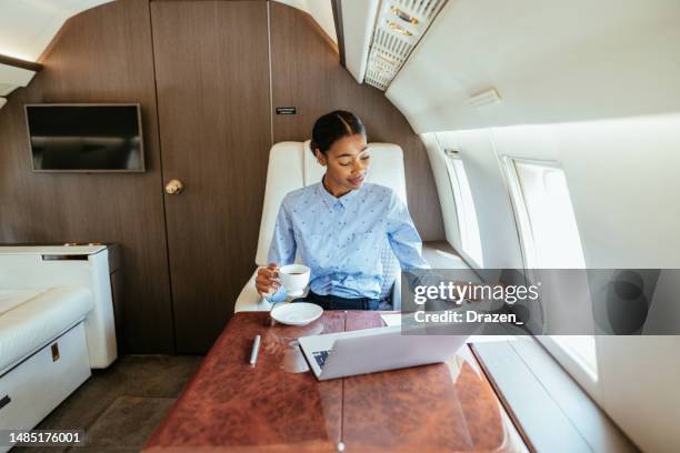 junge afrikanische geschäftsfrau, die mit einem privatflugzeug fliegt und einen laptop für die arbeit nutzt - private aeroplane stock-fotos und bilder