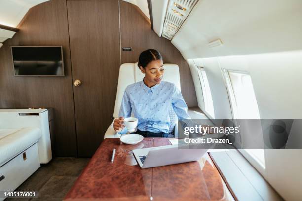 young african businesswoman flying by private airplane and using laptop for work - jet privé stockfoto's en -beelden