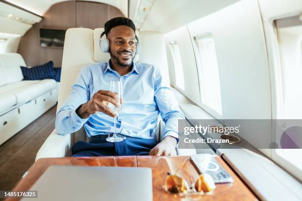 smiling african businessman flying by private jet and looking through the window - airport business lounge stock pictures, royalty-free photos & images