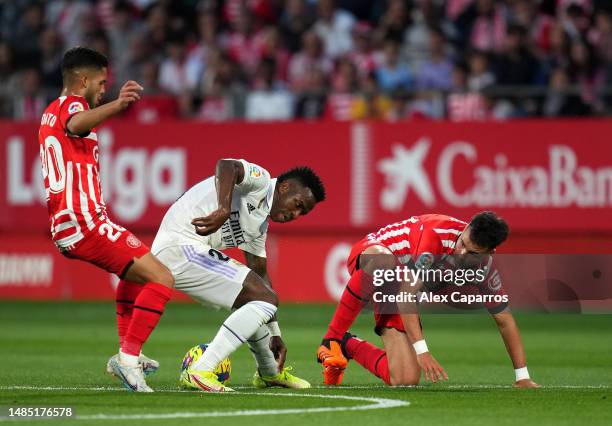 Vinicius Junior of Real Madrid battles for possession with Yan Couto and Arnau Martinez of Girona FC during the LaLiga Santander match between Girona...