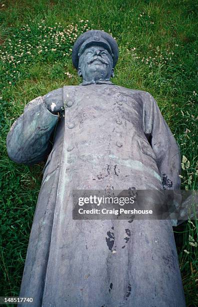 a statue of stalin, relegated to the scrap heap after the fall of communism, lying on the grass at the lenin and stalin graveyard - stalin statue stock pictures, royalty-free photos & images