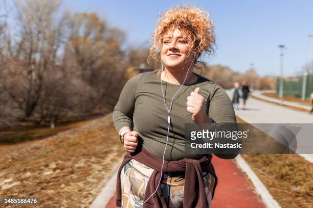 woman with curly hair running on a sunny day - fat loss training stockfoto's en -beelden