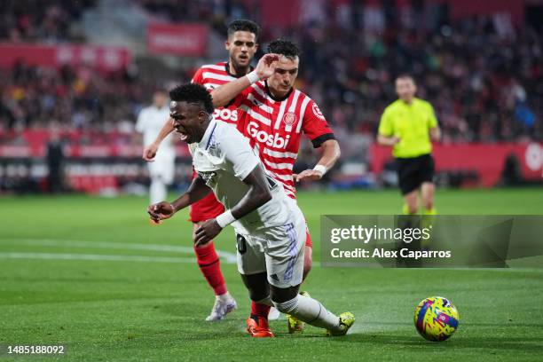 Vinicius Junior of Real Madrid is challenged by Arnau Martinez of Girona FC during the LaLiga Santander match between Girona FC and Real Madrid CF at...