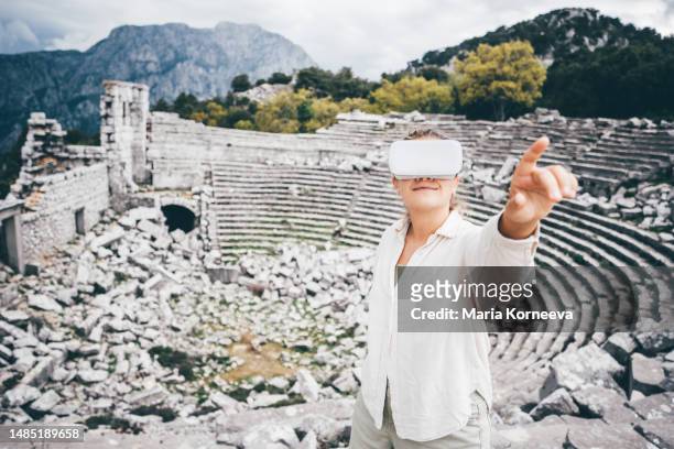 woman in vr headset standing in historical antique amphitheatre. concept of virtual museum. - international landmark stock pictures, royalty-free photos & images