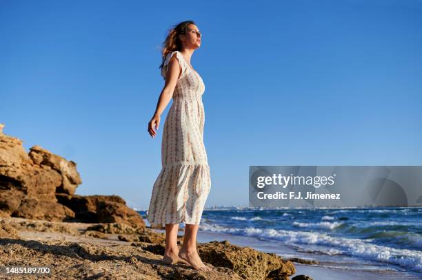 woman in dress at sunset on the beach - woman long dress beach stock pictures, royalty-free photos & images